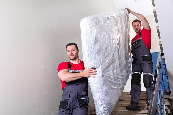 team of workers maneuvering a box spring through a doorway in Dittmer